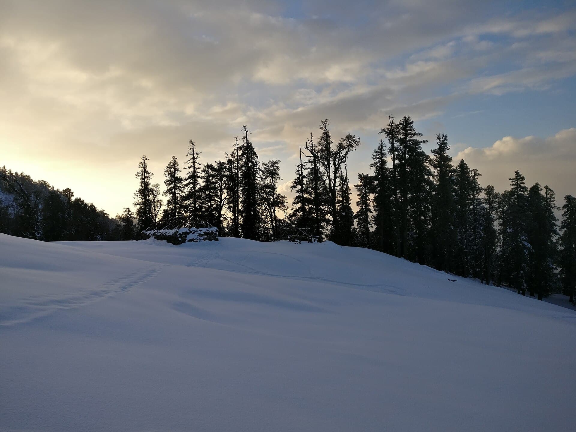 Tents pitched at the Kedarkantha base camp with snow-dusted ridgelines behind