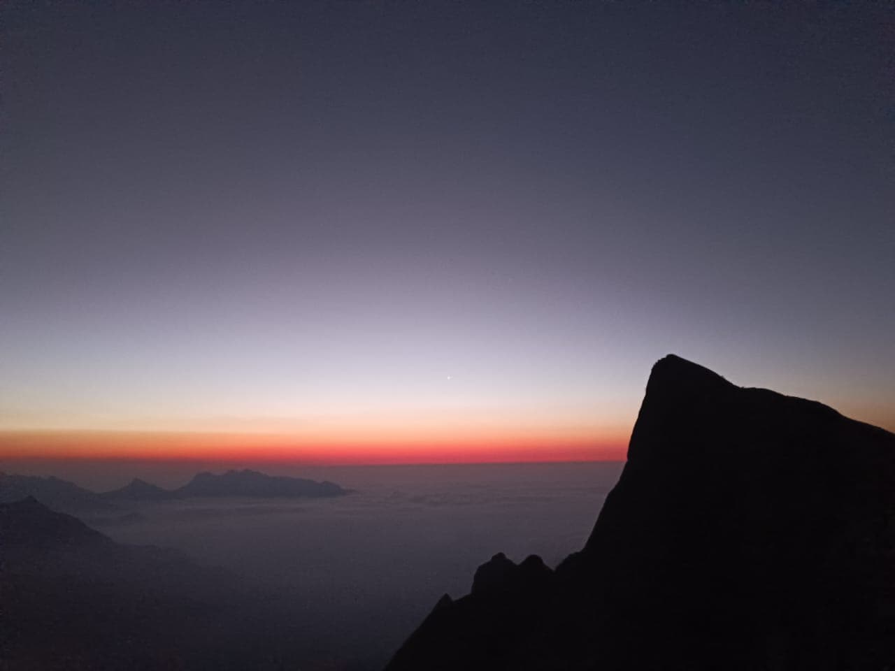 Sunrise breaking over layered mountain ridges and tea plantations at Kolukkumalai